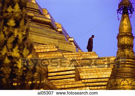 Stock Photo - Myanmar (Burma), Yangon (Rangoon), A monk walking amidst the spires of the Shwedagon Pagoda.. Fotosearch