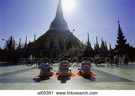 Stock Image - Myanmar (Burma), Yangon (Rangoon), Silhouette of worshippers praying at the Shwedagon Pagoda. Fotosearch