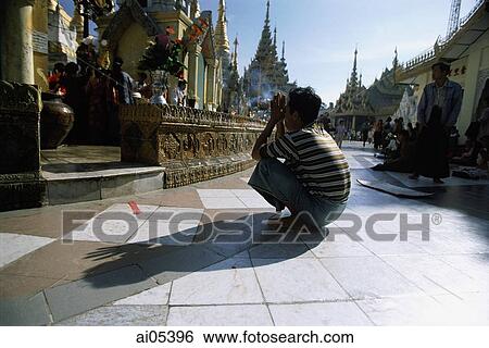 Stock Photograph - Myanmar (Burma), Yangon (Rangoon), Worshipper praying at Shwedagon Pagoda. Fotosearch