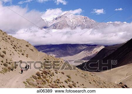 Stock Photo - Nepal, Mustang, Tourists walking along high path, surrounded by mountains.. Fotosearch