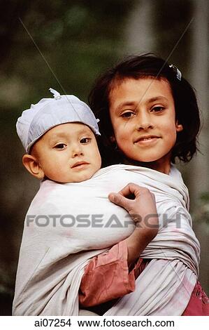 Pakistan, Northern Areas, Hunza Valley, Karimabad, Portrait of girl carrying baby. View Large Photo Image Picture - Pakistan, Northern Areas, Hunza Valley, Karimabad, Portrait of girl carrying baby.. Fotosearch