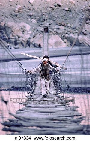 Pakistan, Northern Areas, Hunza Valley, Villagers crossing rope bridge. View Large Photo Image Picture - Pakistan, Northern Areas, Hunza Valley, Villagers crossing rope bridge.. Fotosearch