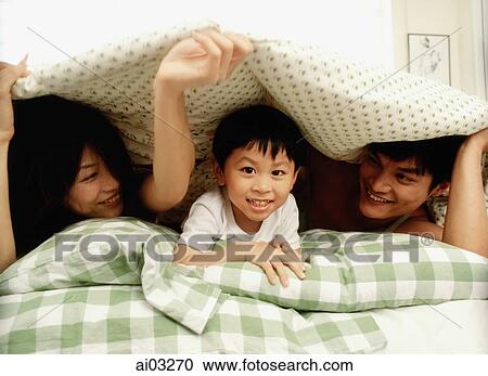 Parents and child in bed, playing View Large Photo Image Stock Image - Parents and child in bed, playing. Fotosearch