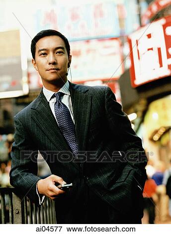 Stock Photo - Portrait of executive holding cellular phone on street.. Fotosearch