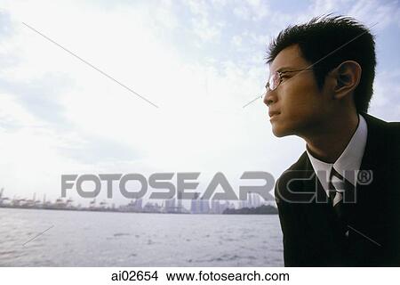 Profile of male executive looking across water, blue sky in background View Large Photo Image Picture - Profile of male executive looking across water, blue sky in background. Fotosearch