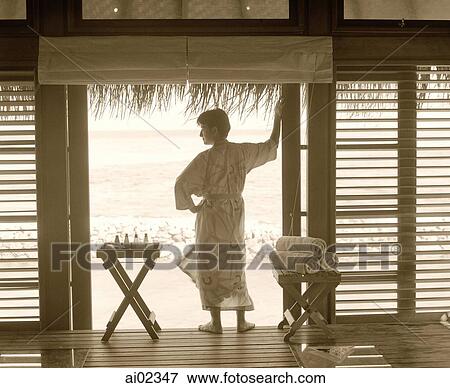 Stock Photo - Profile of man standing at doorway, sea in background. Fotosearch