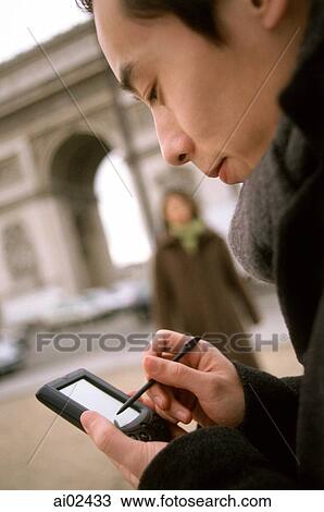 Stock Image - Profile of man using PDA, Arc de Triomphe in background.. Fotosearch