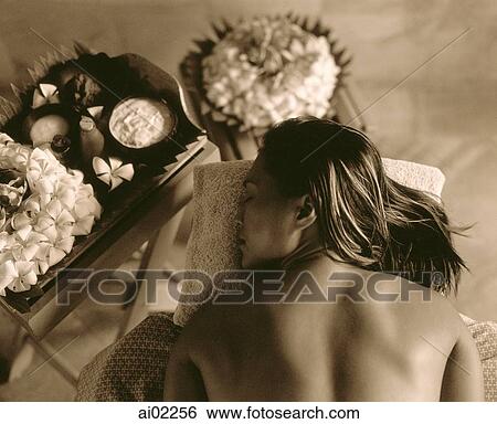 Stock Photograph - Profile of woman lying down with flowers on table next to her. Fotosearch