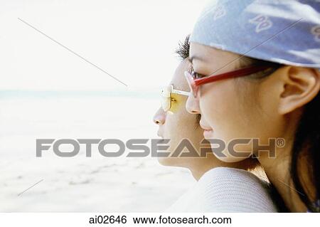 Profile of young couple with sunglasses on beach, woman leaning on back of man View Large Photo Image Stock Photograph - Profile of young couple with sunglasses on beach, woman leaning on back of man. Fotosearch