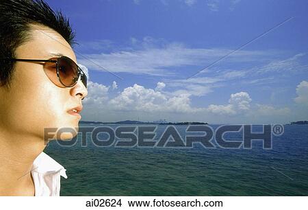 Profile of young man with sunglasses, blue sky in background View Large Photo Image Picture - Profile of young man with sunglasses, blue sky in background. Fotosearch