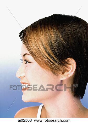 Stock Image - Profile of young woman smiling, portrait. Fotosearch