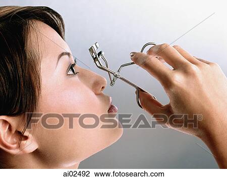 Profile of young woman using an eyelash curler View Large Photo Image Stock Image - Profile of young woman using an eyelash curler. Fotosearch