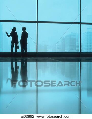 Silhouette of male and female executives by large window, skyline outside. View Large Photo Image Stock Image - Silhouette of male and female executives by large window, skyline outside.. Fotosearch