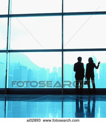 Silhouette of male and female executives by large window, skyline outside. View Large Photo Image Stock Image - Silhouette of male and female executives by large window, skyline outside.. Fotosearch
