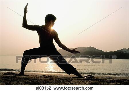 Stock Image - Silhouette of man doing Kung Fu moves at beach. Fotosearch