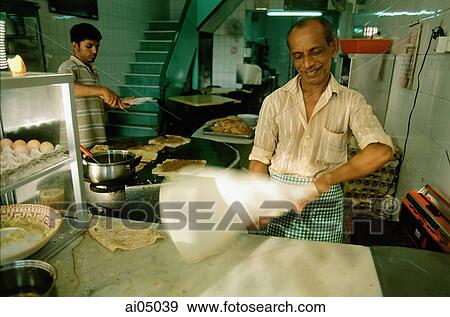 Stock Photo - Singapore, a Muslim chef tossing murtabak, a thick pancake stuffed with meat, egg and onions at a food stall on Arab Street.. Fotosearch