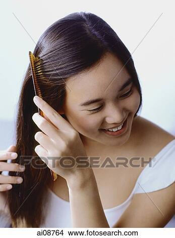 Picture - Teenage girl combing hair, smiling.. Fotosearch