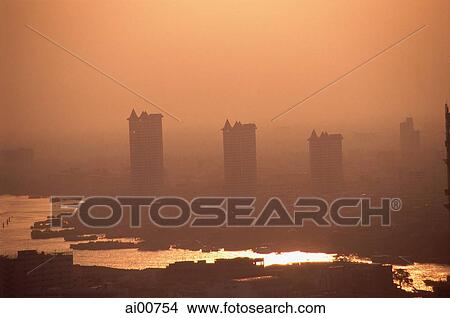 Picture - Thailand, Bangkok, Condominiums seen through the smog across the Chao Praya River. Fotosearch