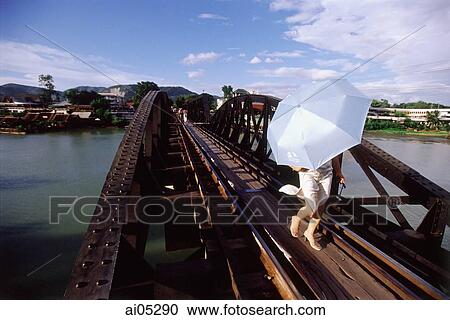 Thailand, Kanchanaburi, River Kwai, A woman crossing the bridge with an umbrella to shield her from the sun. View Large Photo Image Stock Image - Thailand, Kanchanaburi, River Kwai, A woman crossing the bridge with an umbrella to shield her from the sun.. Fotosearch