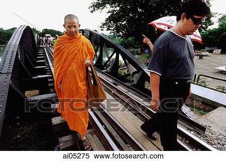 Stock Photography - Thailand, Kanchanaburi, River Kwai, A monk walking over the bridge, along with other tourists.. Fotosearch