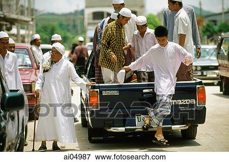 Stock Photo - Thailand, Worshippers dress in traditional garb arrive for Friday prayers in the back of a pickup truck.. Fotosearch