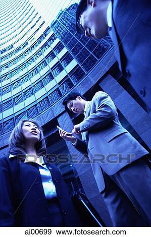 Three executives with buildings behind, low angle view View Large Photo Image Stock Photo - Three executives with buildings behind, low angle view. Fotosearch
