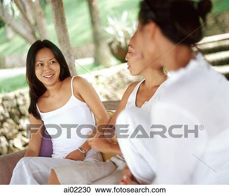 Three women wearing white, sitting together on bench talking View Large Photo Image Stock Image - Three women wearing white, sitting together on bench talking. Fotosearch