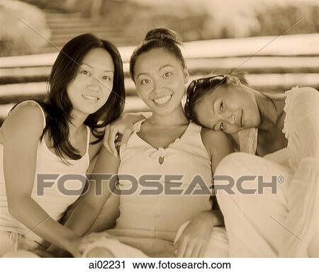 Stock Image - Three women wearing white, sitting together. Fotosearch