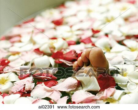 Stock Image - Toes emerging from floating flowers in water.. Fotosearch