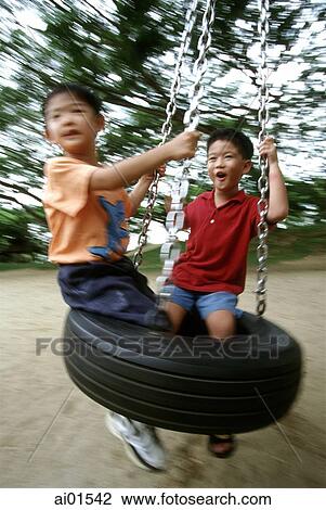 Two boys playing on a swing View Large Photo Image Stock Image - Two boys playing on a swing. Fotosearch