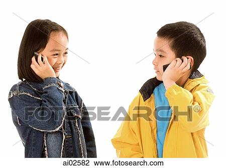 Stock Image - Two children (boy and girl) talking on cellular phones, white background.. Fotosearch