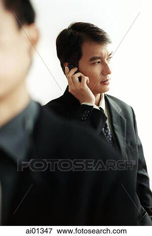Stock Photo - Two male executives, one talking on cellular phone.. Fotosearch