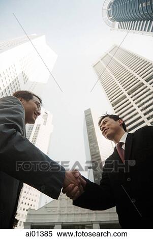 Two male executives shaking hands, low angle view. View Large Photo Image Stock Photography - Two male executives shaking hands, low angle view.. Fotosearch