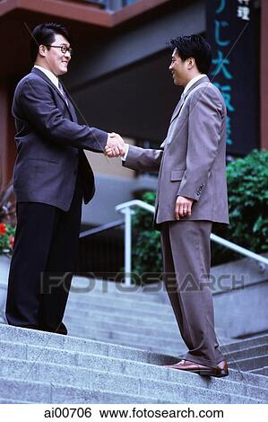 Two male executives shaking hands on stairway View Large Photo Image Stock Photograph - Two male executives shaking hands on stairway. Fotosearch