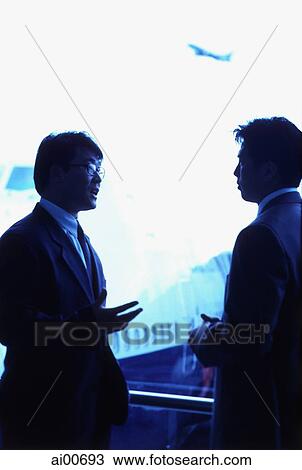 Stock Image - Two male executives talking in airport lounge. Fotosearch
