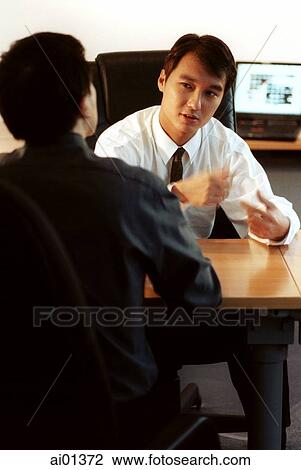 Stock Image - Two male executives talking, one rear view.. Fotosearch