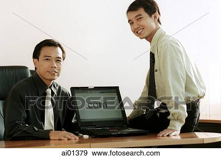 Stock Photo - Two male executives with laptop computer.. Fotosearch