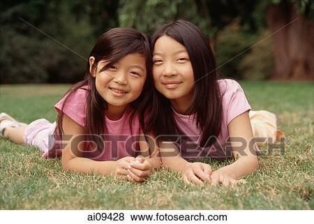 Two sisters lying on grass View Large Photo Image Stock Photo - Two sisters lying on grass. Fotosearch