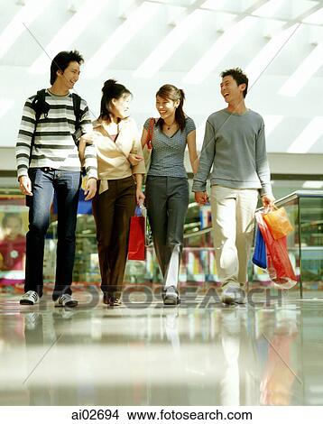 Two young men and two young women walking in shopping mall. View Large Photo Image Picture - Two young men and two young women walking in shopping mall.. Fotosearch