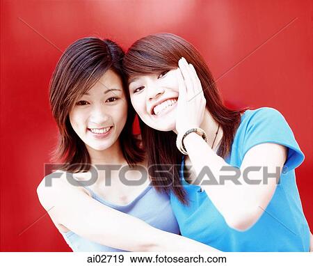 Two young women leaning against each other, smiling, red background. View Large Photo Image Stock Photo - Two young women leaning against each other, smiling, red background.. Fotosearch