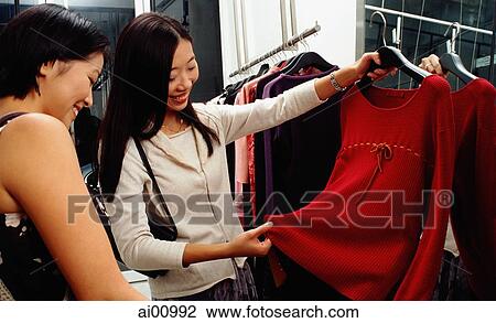 Two young women looking at dress View Large Photo Image Stock Image - Two young women looking at dress. Fotosearch