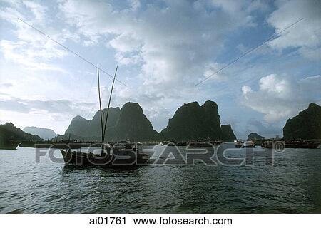 Stock Image - Vietnam, Halong Bay, fishing boat under cloudy sky.. Fotosearch
