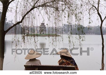 Vietnam, Hanoi, Two women sit on a bench overlooking Huan Kiem Lake. View Large Photo Image Stock Photography - Vietnam, Hanoi, Two women sit on a bench overlooking Huan Kiem Lake.. Fotosearch