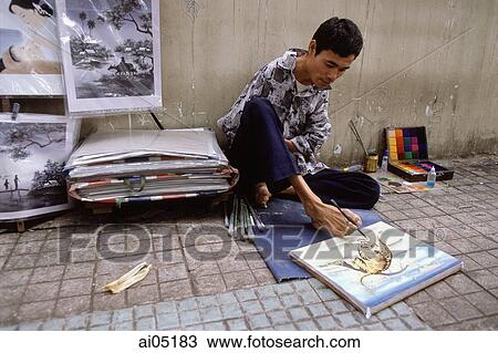 Stock Image - Vietnam, Ho Chi Minh City, A handicapped artist on a sidewalk drawing with his feet.. Fotosearch