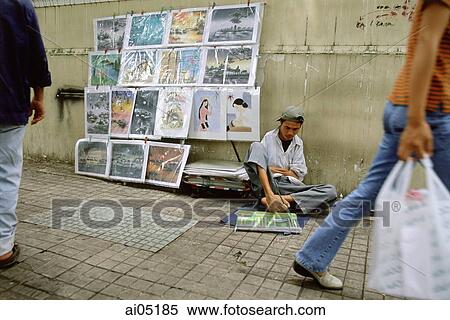 Stock Photography - Vietnam, Ho Chi Minh City, A handicapped artist on a sidewalk drawing with his feet.. Fotosearch