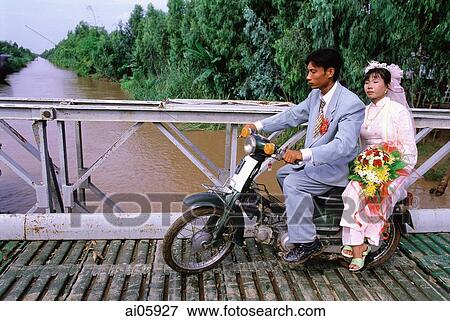 Vietnam, Mekong Delta region, Long Xuyen, Bride and groom on moped crossing bridge. View Large Photo Image Stock Photo - Vietnam, Mekong Delta region, Long Xuyen, Bride and groom on moped crossing bridge.. Fotosearch