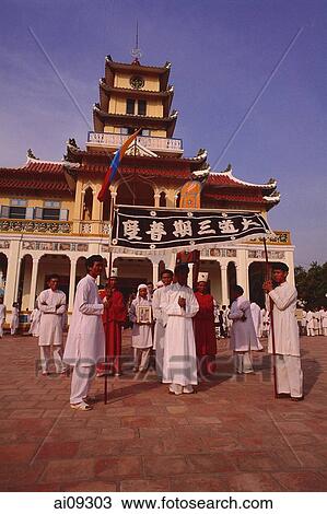 Stock Image - Vietnam, Tay Ninh, Funeral flag bearers and devotees outside Holy See Temple.. Fotosearch