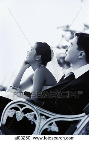 Wedding couple sitting on bench, looking View Large Photo Image Stock Image - Wedding couple sitting on bench, looking. Fotosearch