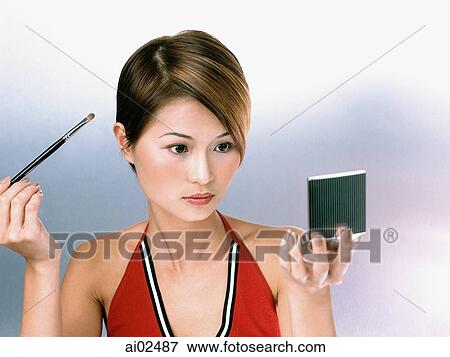 Woman applying eye shadow, looking in compact mirror View Large Photo Image Stock Photo - Woman applying eye shadow, looking in compact mirror. Fotosearch