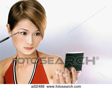 Woman applying eye shadow, looking in compact mirror View Large Photo Image Stock Photo - Woman applying eye shadow, looking in compact mirror. Fotosearch